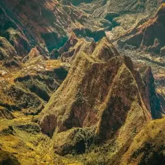 Paysage spectaculaire de montagnes verdoyantes et escarpées, rappelant les défis de la diagonale des fous. Des villages sont nichés dans les vallées.