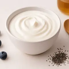 Un bol de yaourt crémeux, des myrtilles, des graines de chia et une cuillère en bois. Un petit-déjeuner sain pour aider à soulager la tendinite.