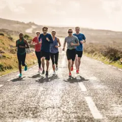 Groupe de coureurs sur une route de campagne ensoleillée. Ils s'entraînent pour comment progresser en course à pied.