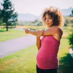 Femme enceinte s'étirant sur un sentier, se demandant si elle peut courir enceinte.