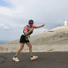 Une coureuse exulte sur la route du semi marathon du Mont Ventoux, le sommet et sa tour en arrière-plan.
