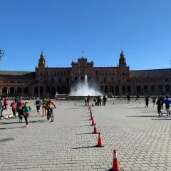 Coureurs et cyclistes s'élancent sur la Plaza de España pour le semi marathon de Séville, sous un ciel bleu éclatant.