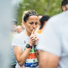 Une coureuse concentrée, mains jointes devant son visage, en pleine préparation mentale marathon.