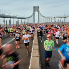 Des coureurs franchissent le pont, affrontant le dénivelé du marathon de New York. Le ciel est couvert, mais l'énergie est palpable.