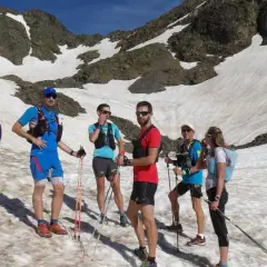 Une équipe de trail sur un sentier enneigé en montagne, profitant d'une journée ensoleillée.