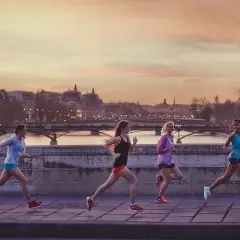 Cinq femmes courent sur un pont à Paris au coucher du soleil, profitant d'une belle soirée pour courir à Paris.