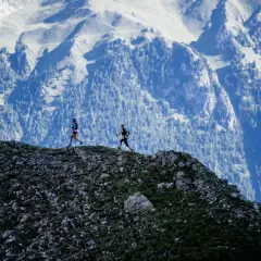 Deux coureurs s'élancent sur le **trail des Fiz**, dominant un paysage montagneux spectaculaire.