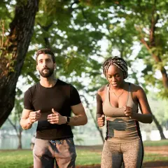 Un homme et une femme courent dans un parc, s'entraînant pour le marathon d'Annecy et son dénivelé.
