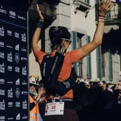 Coureuse célébrant sa victoire à l'UTMB, portant son sac d'hydratation et le matériel obligatoire.
