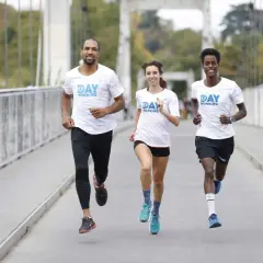 Trois coureurs souriants sur un pont, profitant des bienfaits de la course à pied.
