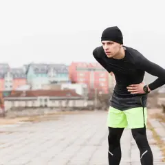 Coureur avec une main sur le ventre, l'air souffrant.