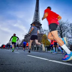 Course de 10 km tour Eiffel, des coureurs en tenue de sport dévalent la route, le monument parisien en arrière-plan.