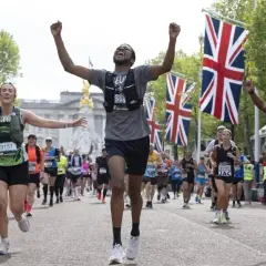 Des coureurs célèbrent leur arrivée au plus grand marathon du monde, drapeaux britanniques en arrière-plan.