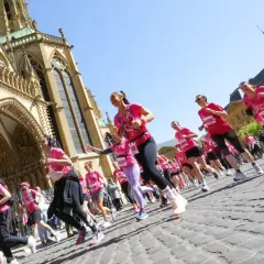 Course de femmes en rose lors du semi-marathon de Tulle, devant une cathédrale majestueuse.