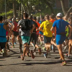 Un groupe de coureurs s'élance sur un chemin, certains portent un gilet lesté pour un entraînement plus intense.