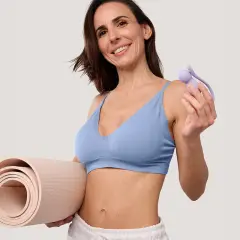 Femme souriante tenant un rouleau de tapis et un accessoire pour muscler son périnée.