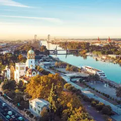 Vue aérienne de Séville au coucher du soleil, avec le Guadalquivir et des bâtiments historiques. Imaginez les coureurs du marathon de Séville 2026 traversant ce paysage.