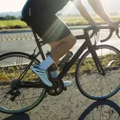 Cycliste en pleine action, profitant d'une belle journée pour le vélo et la course à pied. Le soleil brille sur la route.