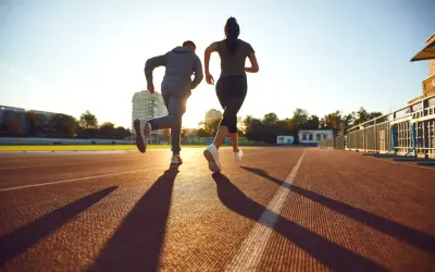 Deux coureurs sur une piste, le soleil couchant projette leurs ombres. Ils s'entraînent, peut-être pour savoir que veut dire EF en course à pied.