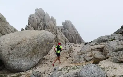 Un coureur en tenue de trail suit le sentier balisé PR-M1, traversant un paysage rocheux et brumeux.