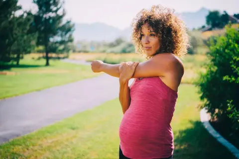 Femme enceinte s'étirant sur un sentier, se demandant si elle peut courir enceinte.