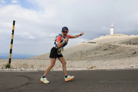 Une coureuse exulte sur la route du semi marathon du Mont Ventoux, le sommet et sa tour en arrière-plan.