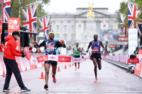 Le coureur Kitata franchit la ligne d'arrivée du marathon de Londres, sous les drapeaux britanniques.