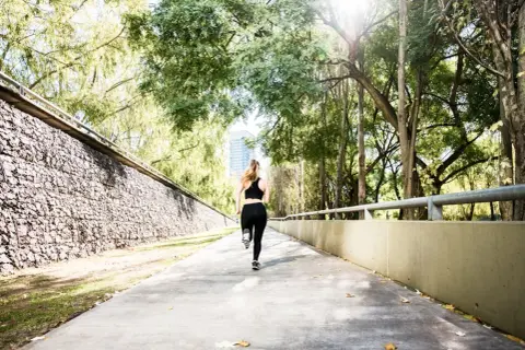 Une femme court sur un chemin ensoleillé, s'entraînant pour le semi marathon Venise.