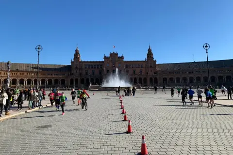 Coureurs et cyclistes s'élancent sur la Plaza de España pour le semi marathon de Séville, sous un ciel bleu éclatant.