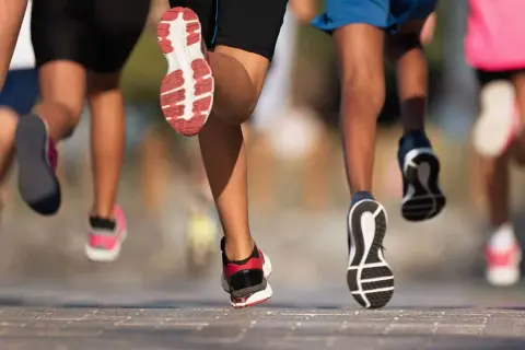 Des coureurs en action, leurs pieds chaussés de baskets s'élancent sur le bitume. Ils font du footing, une course dynamique et énergique.