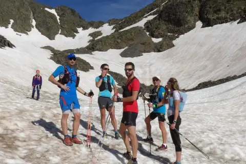 Une équipe de trail sur un sentier enneigé en montagne, profitant d'une journée ensoleillée.