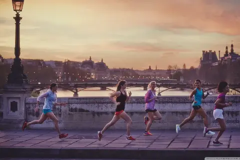 Cinq femmes courent sur un pont à Paris au coucher du soleil, profitant d'une belle soirée pour courir à Paris.
