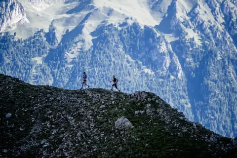 Deux coureurs s'élancent sur le **trail des Fiz**, dominant un paysage montagneux spectaculaire.