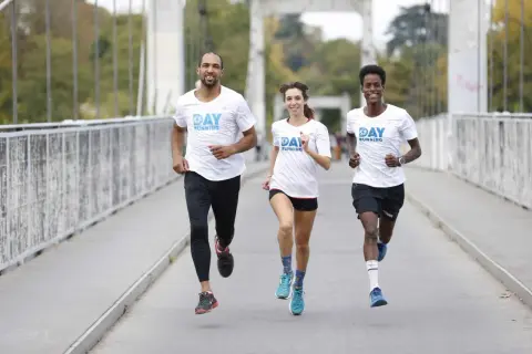 Trois coureurs souriants sur un pont, profitant des bienfaits de la course à pied.