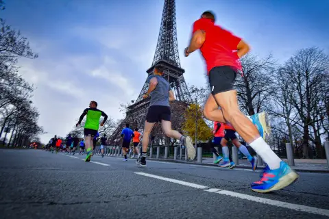 Course de 10 km tour Eiffel, des coureurs en tenue de sport dévalent la route, le monument parisien en arrière-plan.