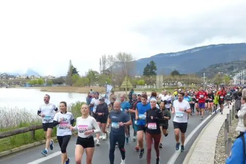 Course à Aix-les-Bains : une foule de coureurs participe à un marathon au bord du lac, avec des montagnes en toile de fond.