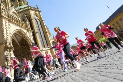 Course de femmes en rose lors du semi-marathon de Tulle, devant une cathédrale majestueuse.
