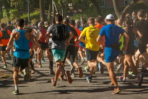 Un groupe de coureurs s'élance sur un chemin, certains portent un gilet lesté pour un entraînement plus intense.