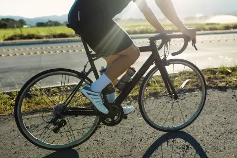 Cycliste en pleine action, profitant d'une belle journée pour le vélo et la course à pied. Le soleil brille sur la route.