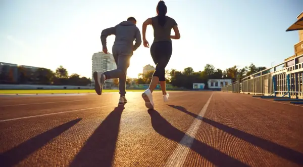 Deux coureurs sur une piste, le soleil couchant projette leurs ombres. Ils s'entraînent, peut-être pour savoir que veut dire EF en course à pied.