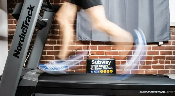 Person en mouvement sur un tapis roulant NordicTrack, simulant des gammes athlétiques. Un panneau "Subway Times Square" est visible.