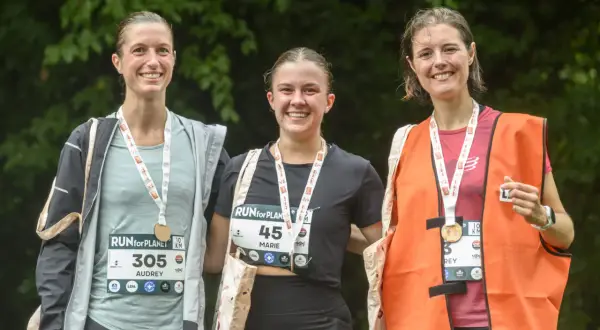 Trois coureuses souriantes, médailles au cou, célèbrent leur participation à la course RUN for PLANET.
