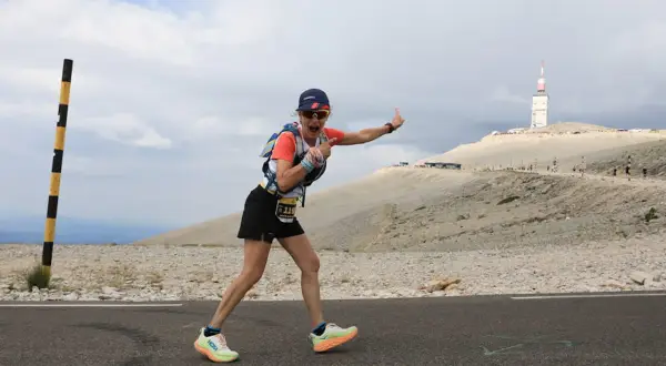 Une coureuse exulte sur la route du semi marathon du Mont Ventoux, le sommet et sa tour en arrière-plan.