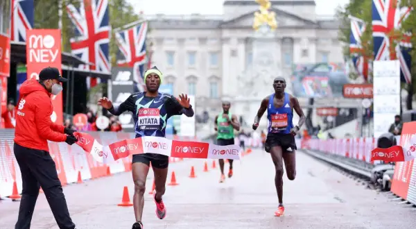 Le coureur Kitata franchit la ligne d'arrivée du marathon de Londres, sous les drapeaux britanniques.