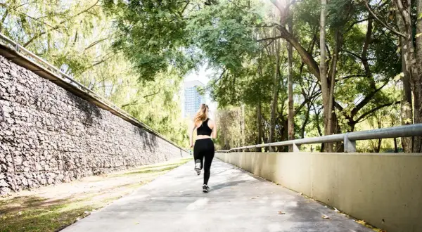 Une femme court sur un chemin ensoleillé, s'entraînant pour le semi marathon Venise.
