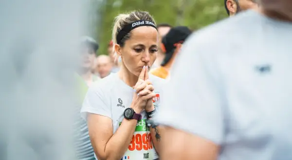 Une coureuse concentrée, mains jointes devant son visage, en pleine préparation mentale marathon.