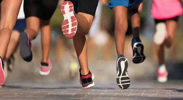 Des coureurs en action, leurs pieds chaussés de baskets s'élancent sur le bitume. Ils font du footing, une course dynamique et énergique.