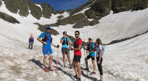 Une équipe de trail sur un sentier enneigé en montagne, profitant d'une journée ensoleillée.