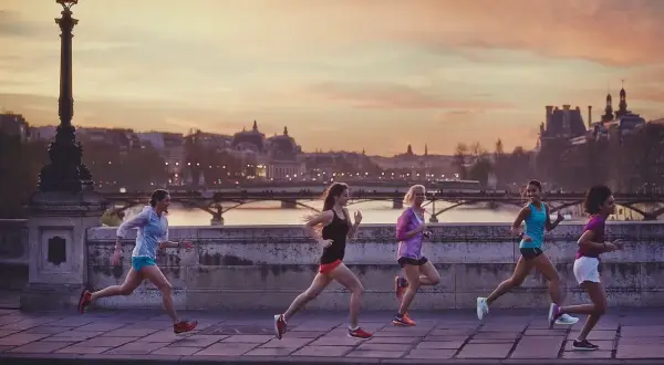 Cinq femmes courent sur un pont à Paris au coucher du soleil, profitant d'une belle soirée pour courir à Paris.