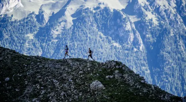 Deux coureurs s'élancent sur le **trail des Fiz**, dominant un paysage montagneux spectaculaire.